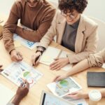A diverse team of professionals collaborating over charts and graphs during a business meeting.